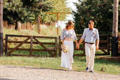 Couple standing on footpath by trees