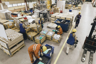 Male and female blue-collar workers in uniform working in factory warehouse