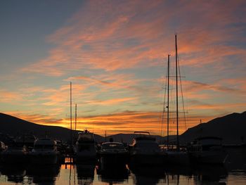 Boats moored at harbor during sunset