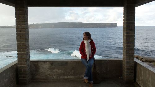 Woman standing by sea against sky