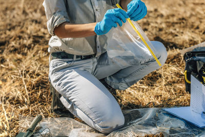 Low section of agronomist analyzing soil on field