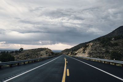 Empty road against cloudy sky