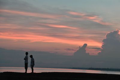 Silhouette couple standing against sky during sunset