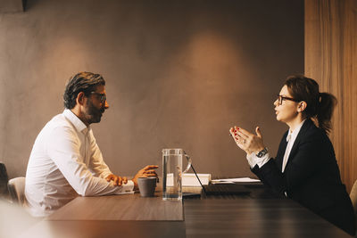 Side view of female lawyer explaining mature client in meeting at office