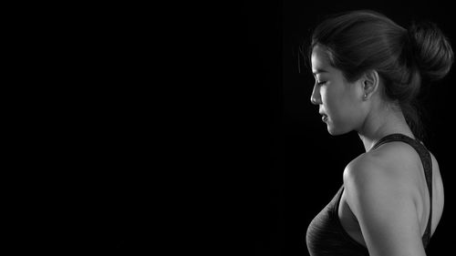 Side view of young woman against black background