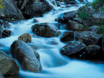 Blurred motion of stream flowing amidst rocks in forest