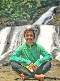 Portrait of smiling man sitting on rock