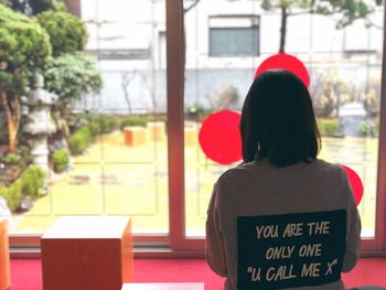 Rear view of woman with text against window
