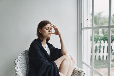 Side view of young woman looking through window