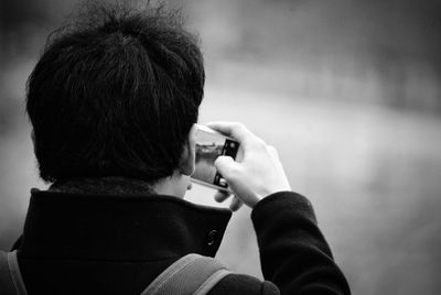 Rear view of man photographing from mobile phone