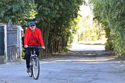 Man riding bicycle on road amidst trees