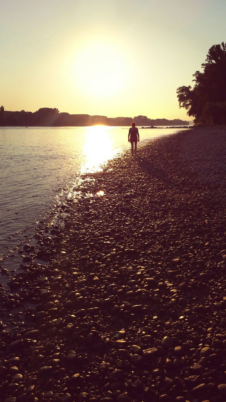 sunset, sun, water, leisure activity, lifestyles, silhouette, sunlight, men, beach, reflection, sea, tranquil scene, person, scenics, nature, sunbeam, tranquility