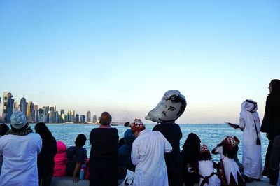 People at beach against clear sky