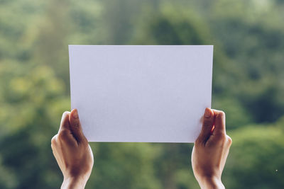 Close-up of hand holding paper against blurred background