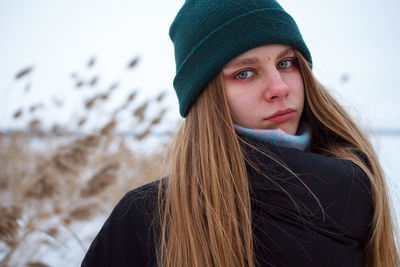 Portrait of young woman in winter against sky