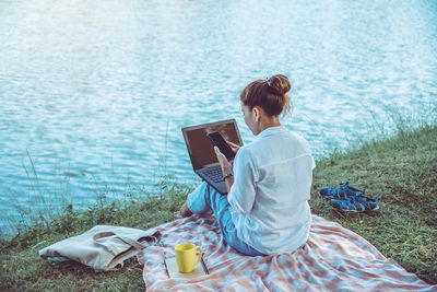 Woman sitting on book by lake