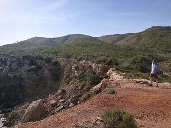 Man hiking on mountain against sky