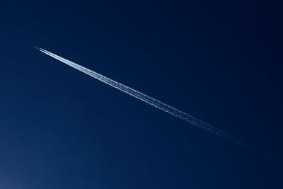 Low angle view of vapor trail against clear blue sky