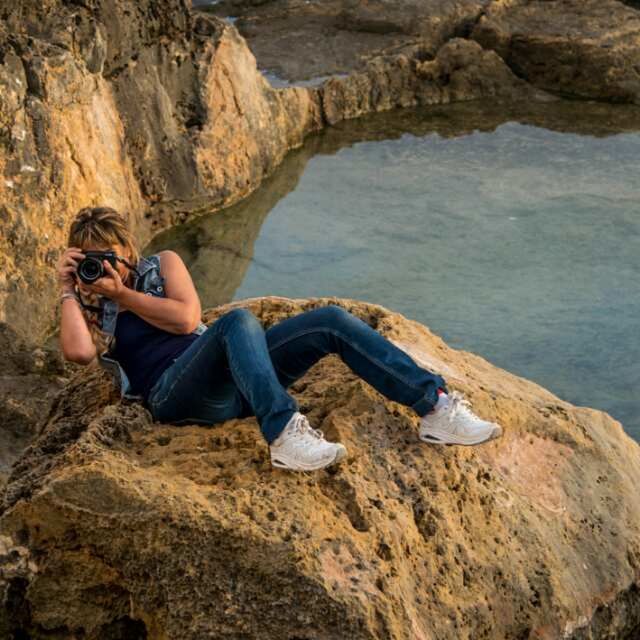 YOUNG WOMAN ON ROCK AT SHORE