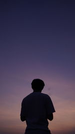 Rear view of silhouette boy standing against sky during sunset