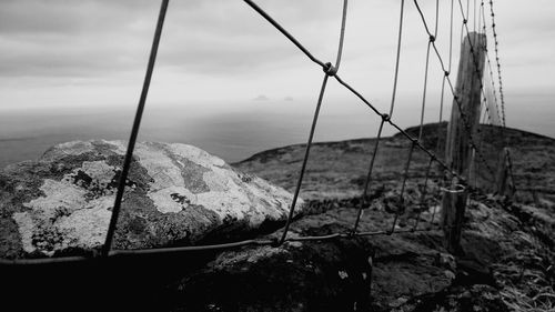 Fence on rock against sea