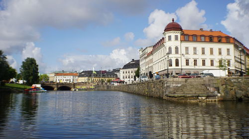 Bridge over river by buildings in city against sky