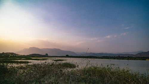 Scenic view of calm lake against cloudy sky