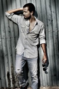 Young man standing against corrugated iron