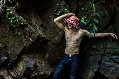 Midsection of woman standing on rock in forest