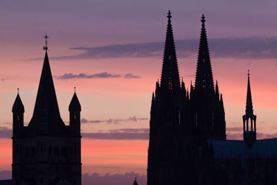 Silhouette churches against dramatic sky at sunset