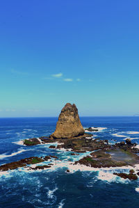 Rock formation on sea against blue sky