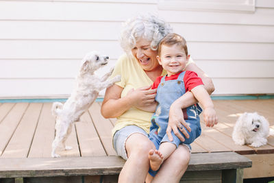 Senior woman and boy with dogs sitting outdoors