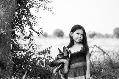 Cute girl standing with german shepherd by tree