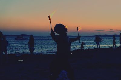 Silhouette man fishing at beach against sky during sunset