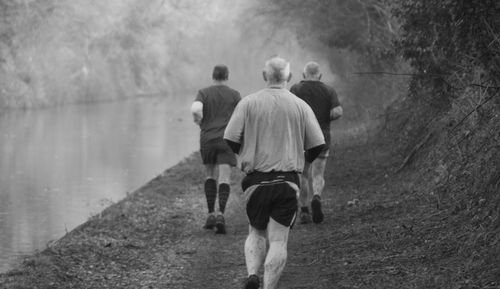 Rear view of men jogging in countryside