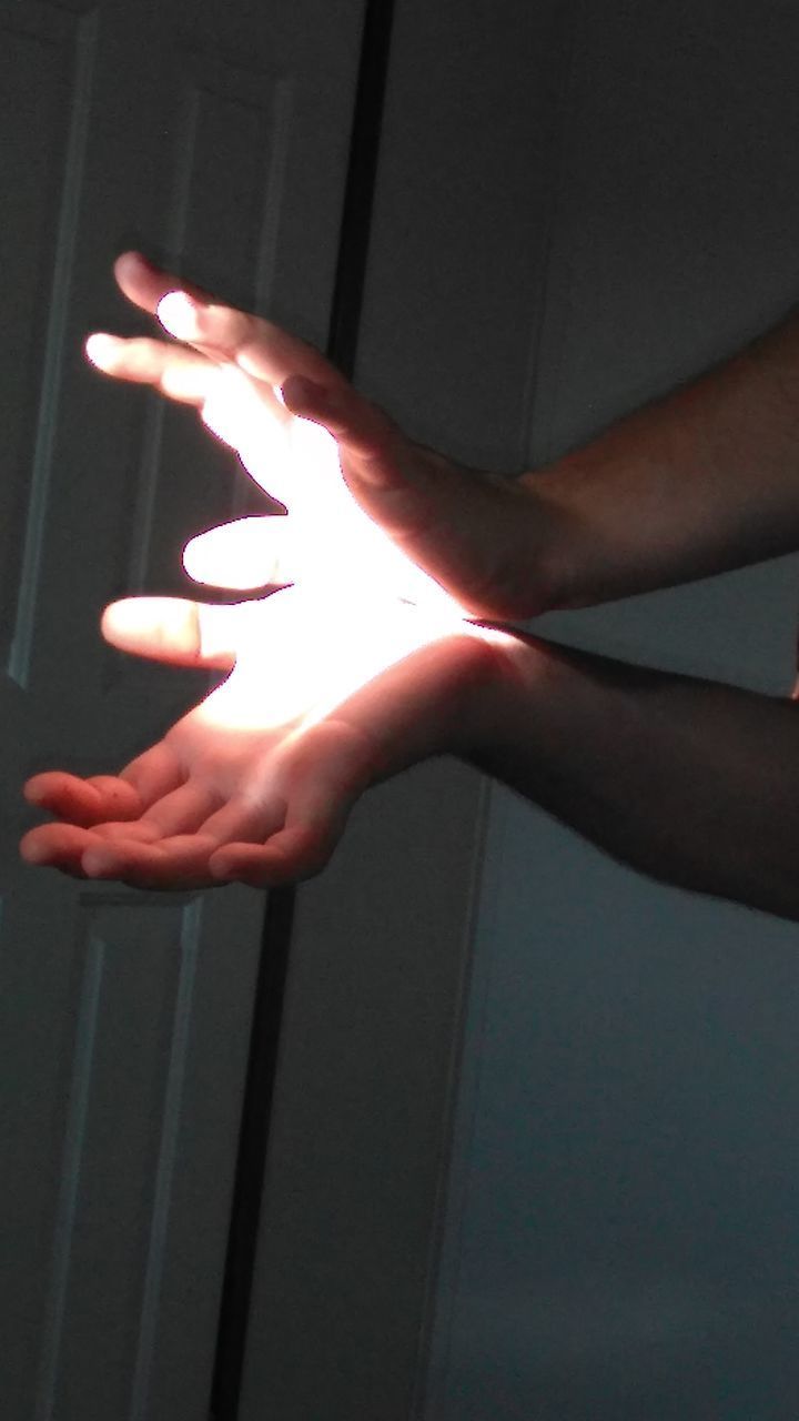 CLOSE-UP OF HAND TOUCHING ILLUMINATED LIGHT