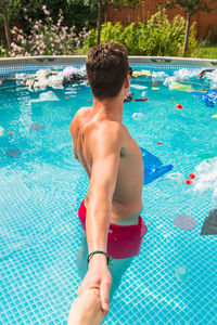 Rear view of shirtless boy swimming in pool