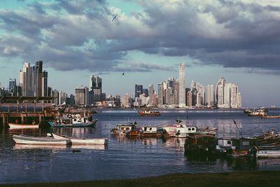 Boats moored on sea against buildings in city