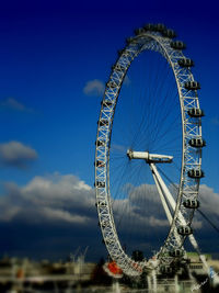 Low angle view of ferris wheel against cloudy sky