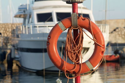 Close-up of life belt on pole against sailboat in sea