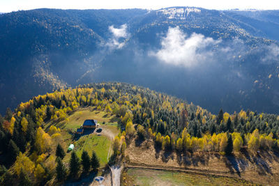 Aerial view of a small countryside homestead and colorful autumn forest. drone point of view