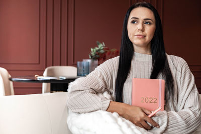 Businesswoman looking away while holding diary