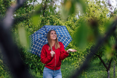 Portrait of young woman standing against plants