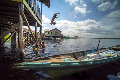 Fishing boats moored in sea against sky