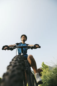 Low angle view of man riding bicycle against clear sky