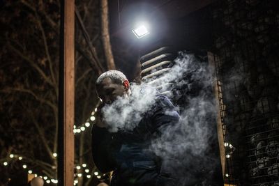 Man smoking by illuminated lights at night