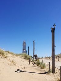 Windmill on beach against clear blue sky