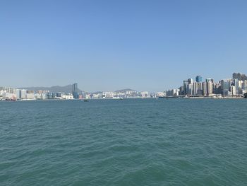 Sea by buildings against clear blue sky