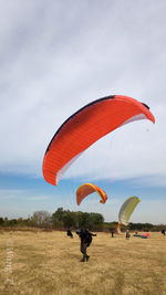 View of people paragliding on landscape against sky