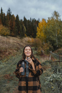 Portrait of smiling young woman standing in forest